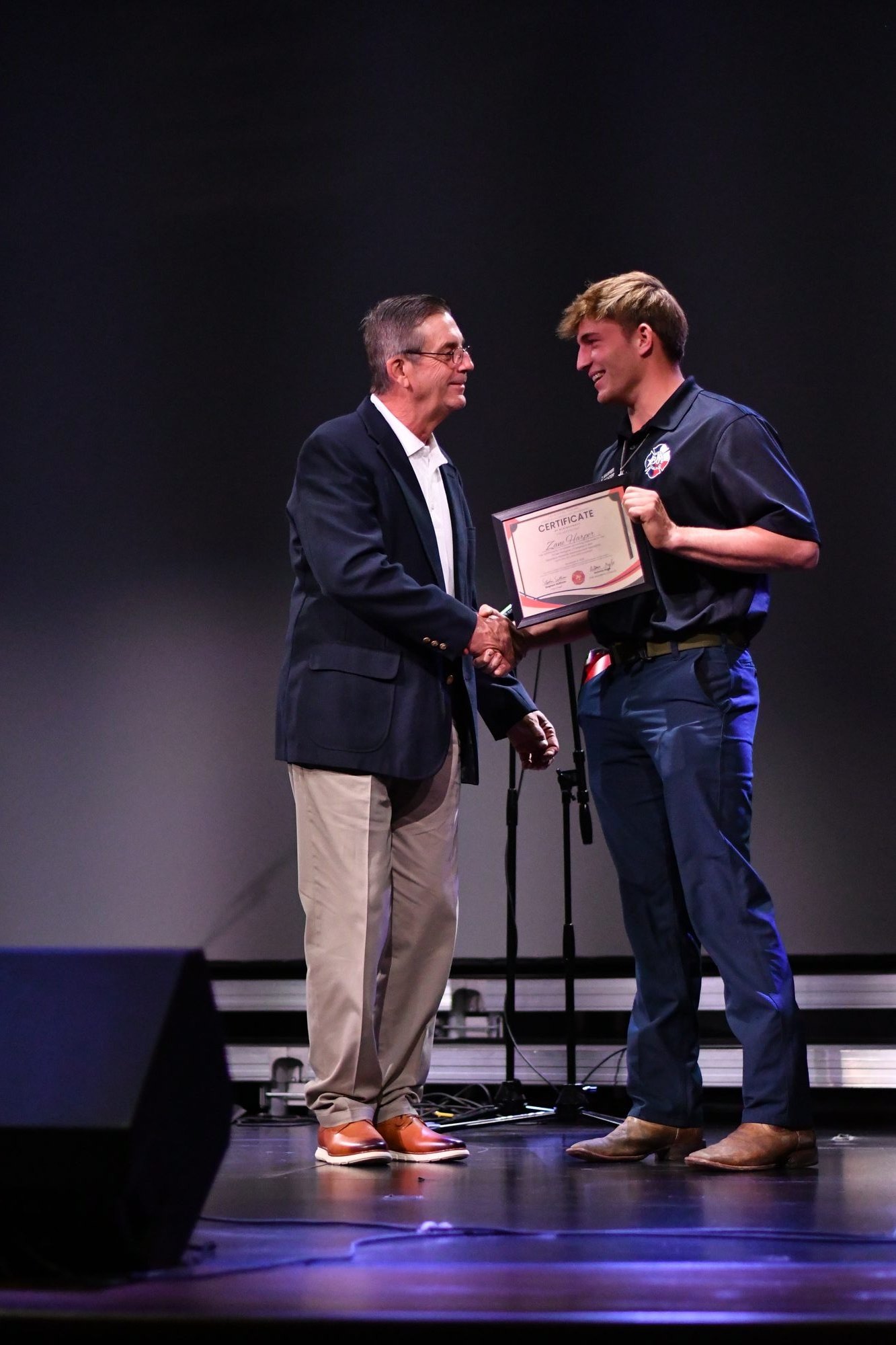 A member is congratulated on stage with a certificate