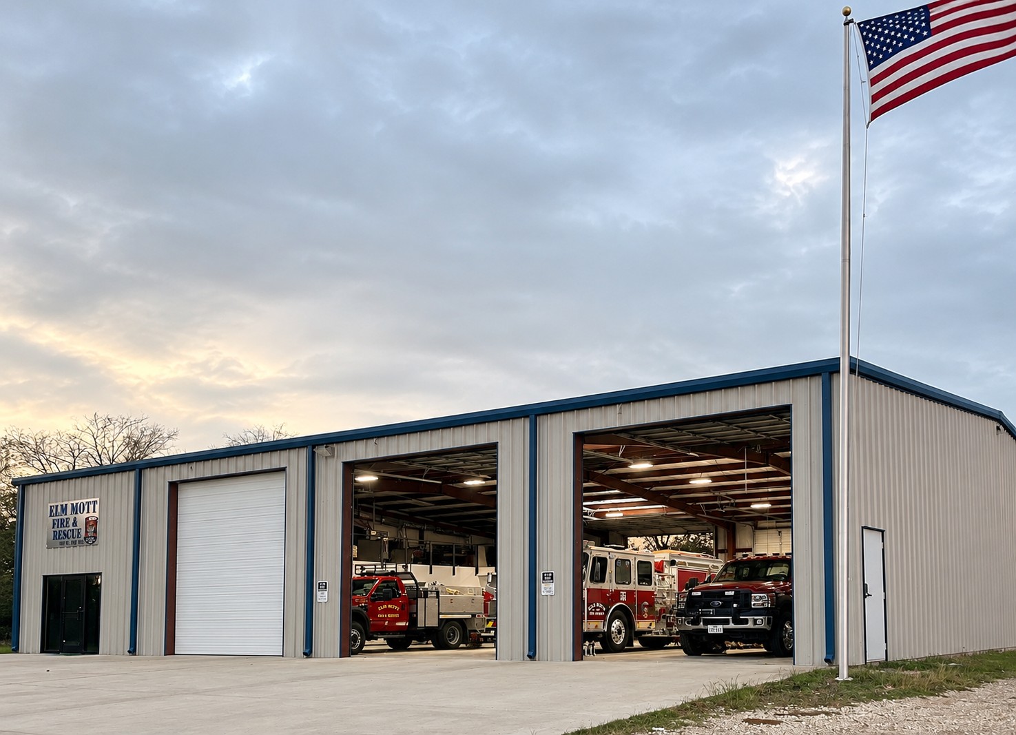 Elm Mott Fire Rescue Station 1 at dusk with the flag flying and bay doors open